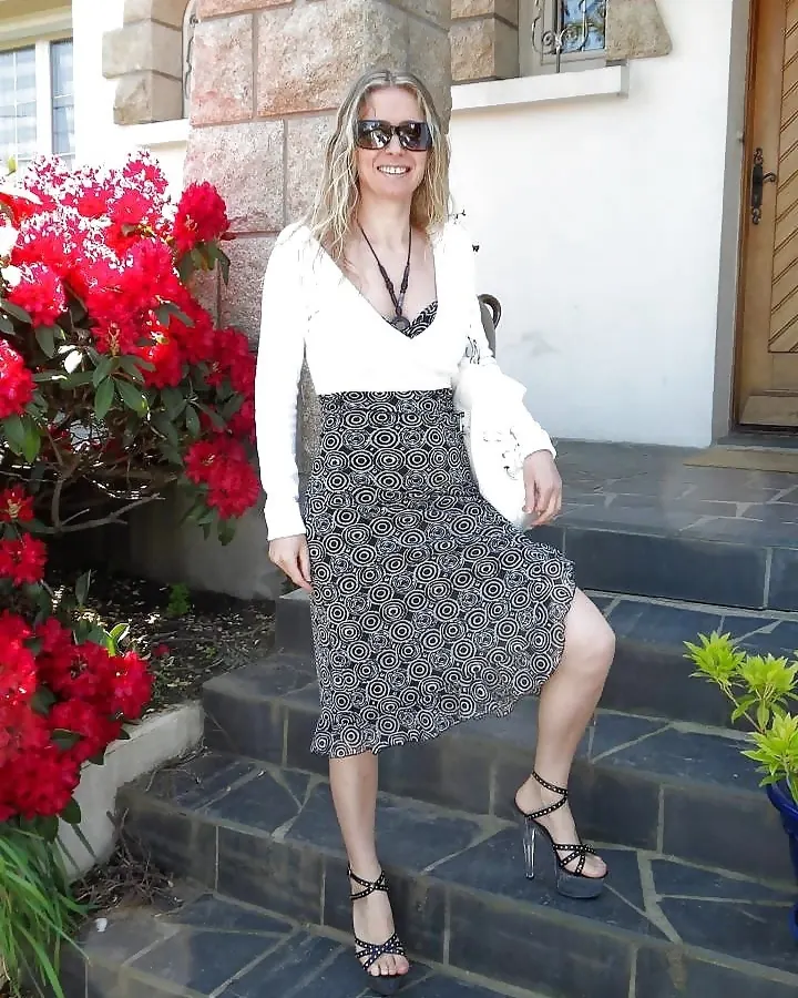 Femme blonde aux lunettes noires, jupe imprimée cercles, talons à brides
